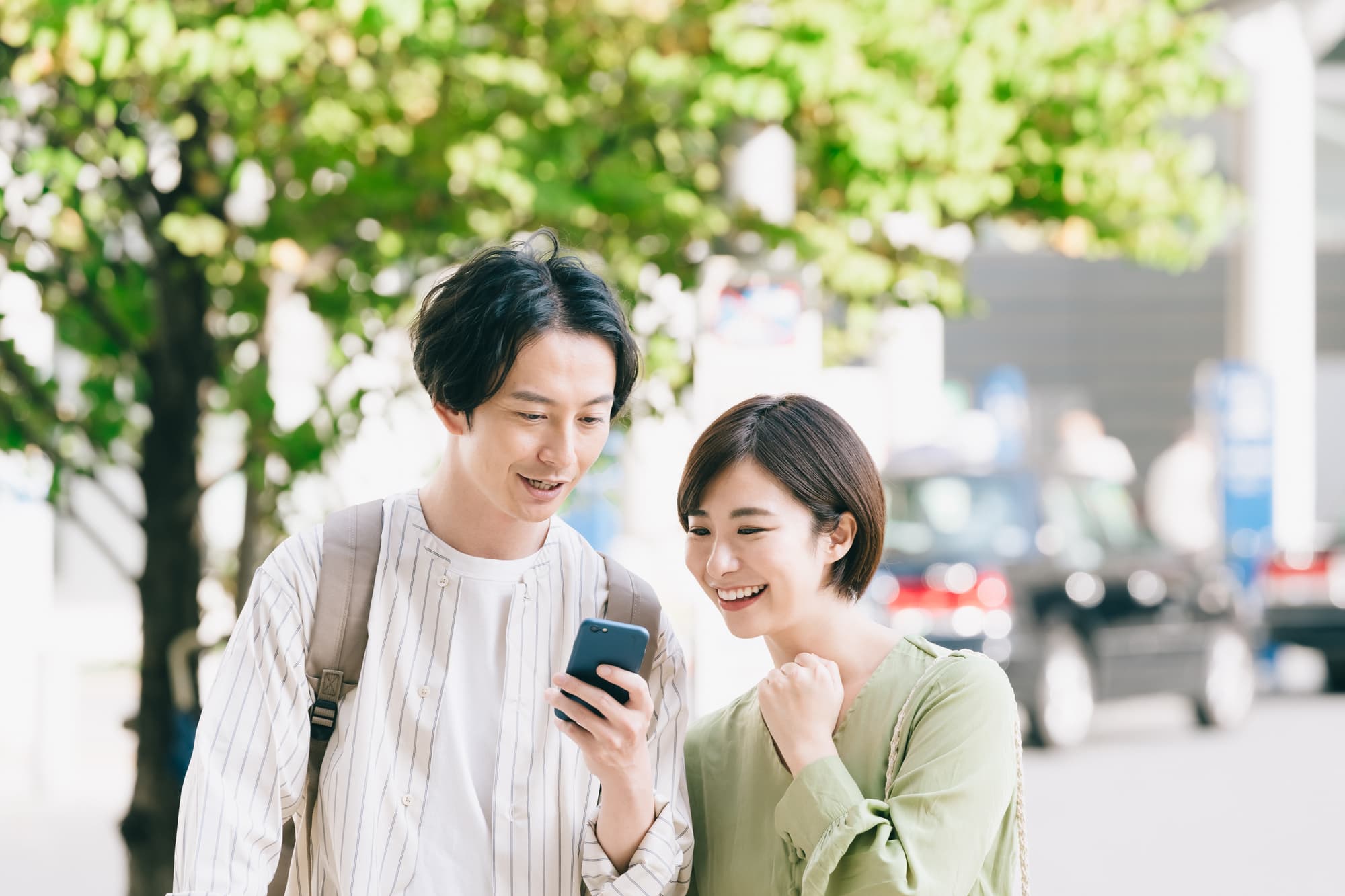 街角で立ち止まりスマホで行先を確認する男女