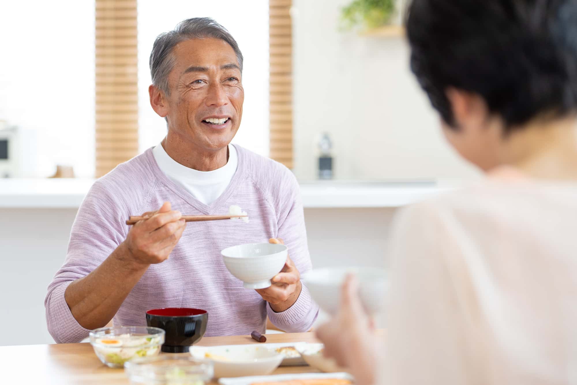 失った歯を補うブリッジ治療をして笑顔で食事をする男性