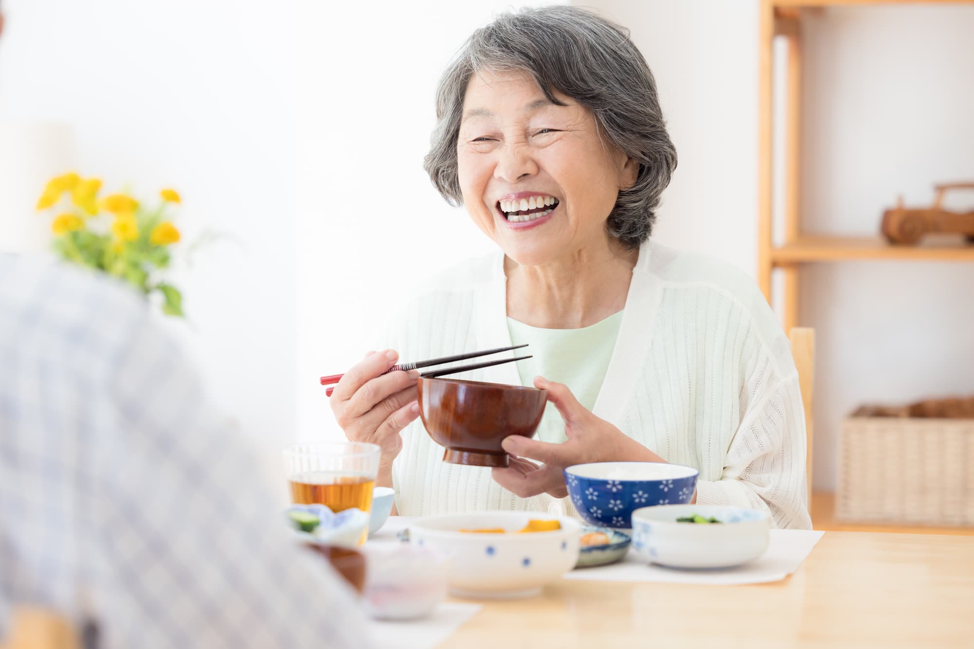 入れ歯を入れて快適に食事をする年配の女性