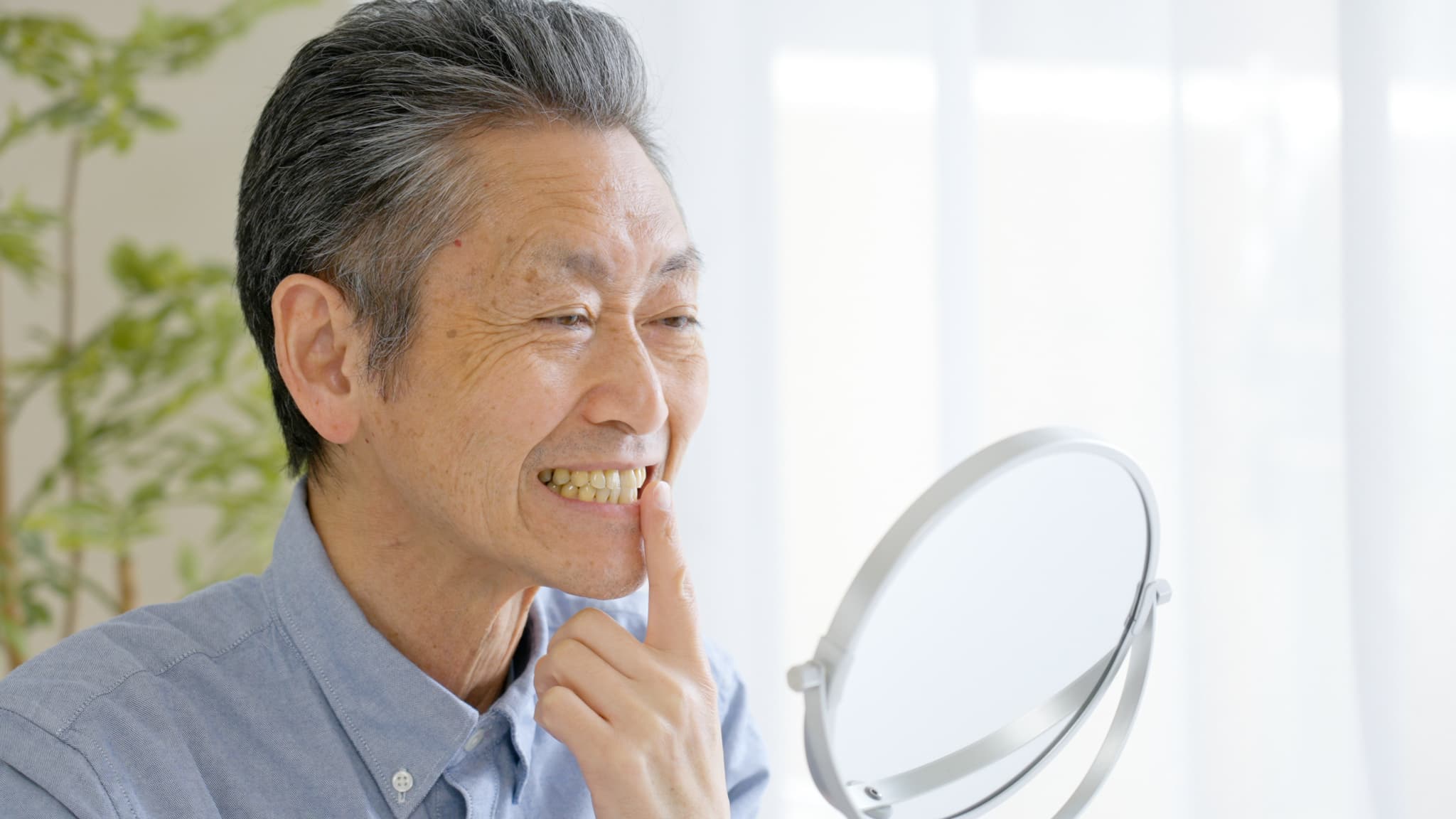 入れ歯の状態を鏡で確認する男性