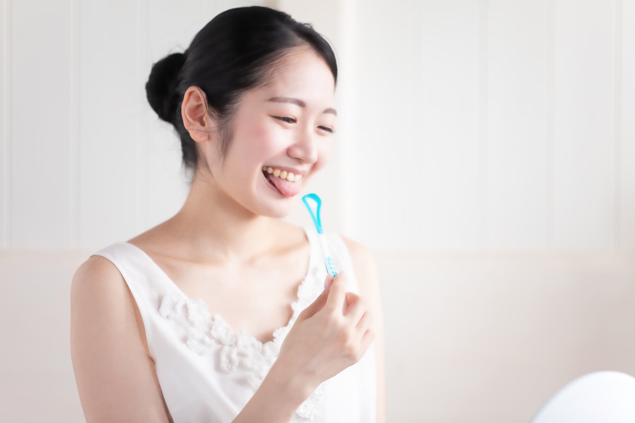 舌ブラシで口臭を確認する女性
