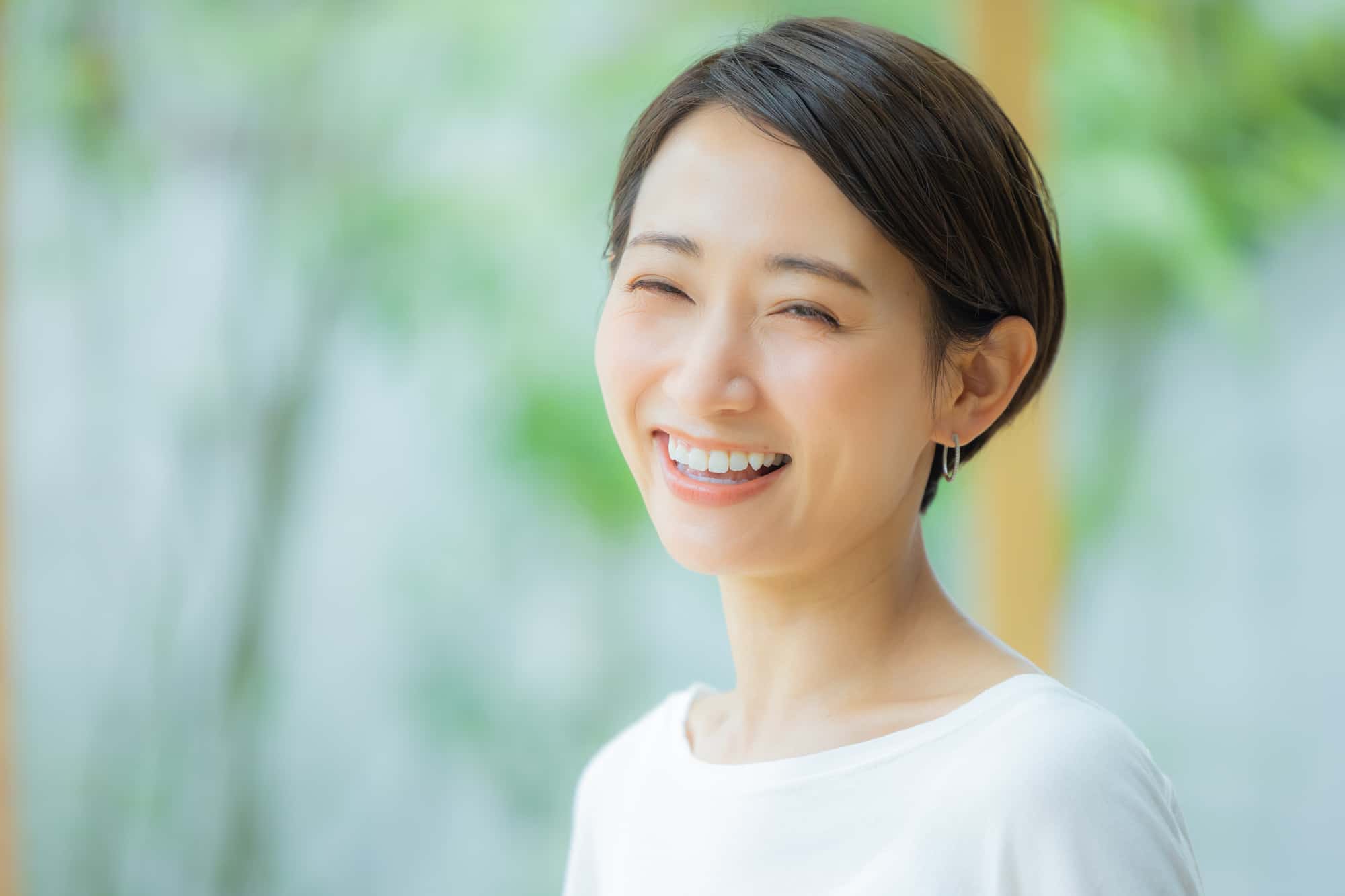 虫歯治療後にホワイトニングをした白い歯で笑う女性